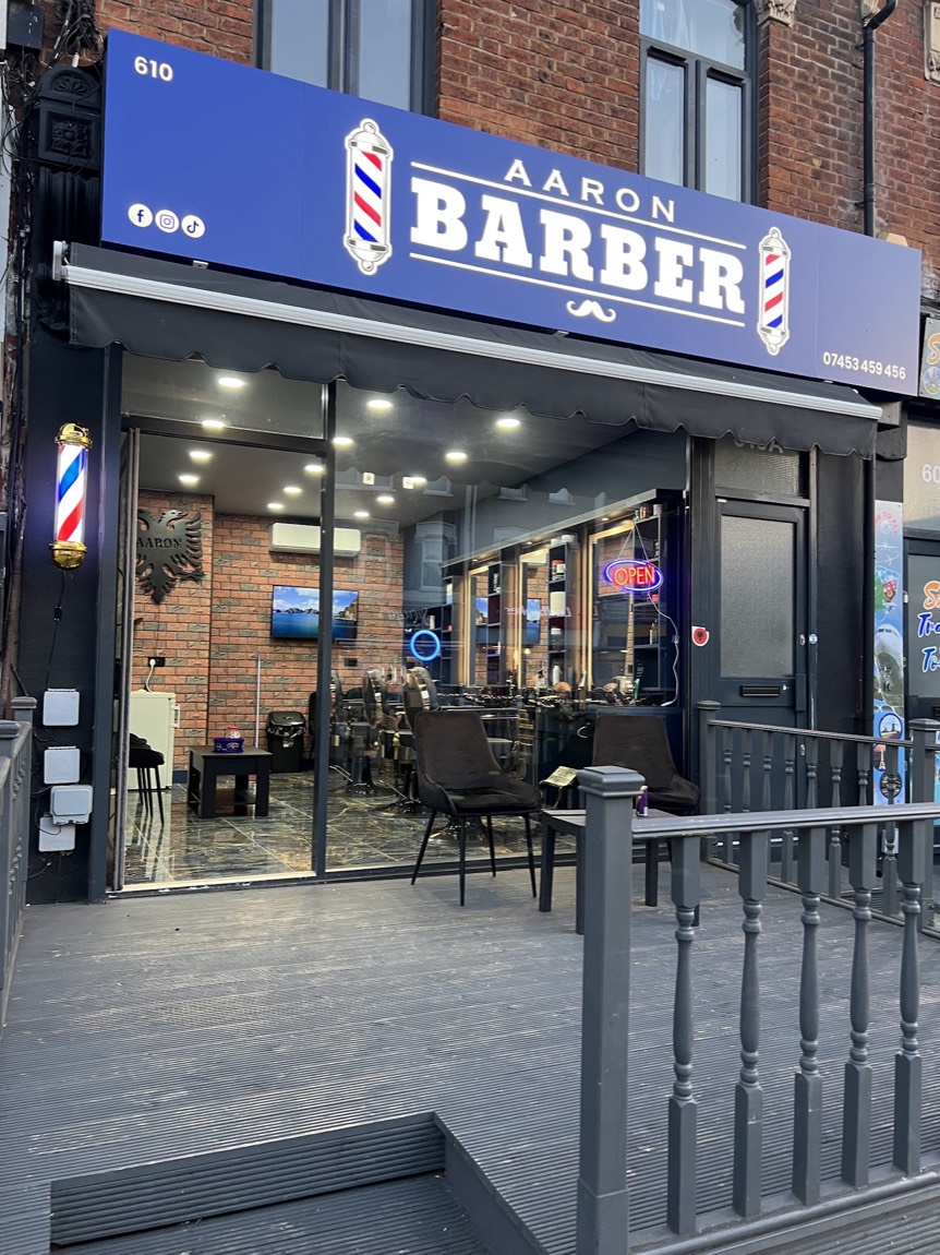 The Aaron Barber shopfront at 610 Romford Road with blue signage and barber pole